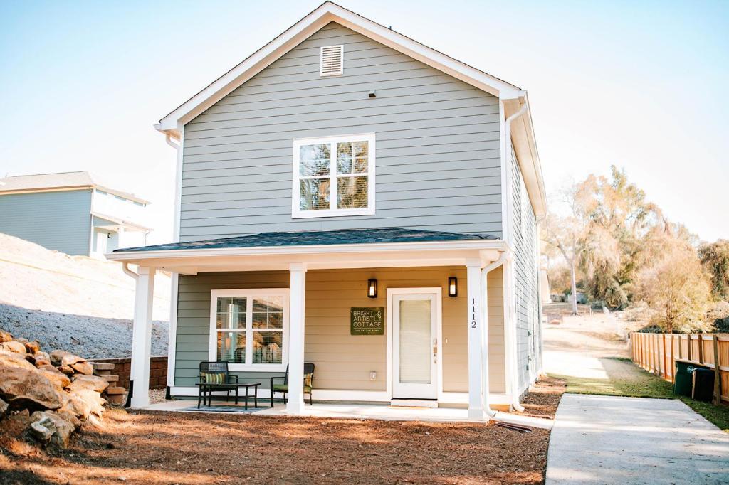 uma casa com um alpendre com um banco em Bright Artist's Cottage - 4br, 1mi To Dt Uga em Athens