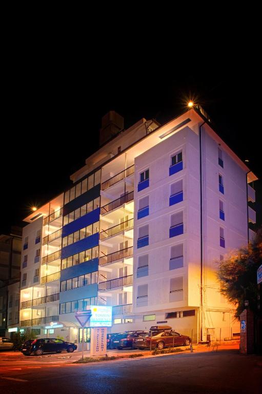 a large white building with cars parked in front of it at Tourist Residence in San Benedetto del Tronto