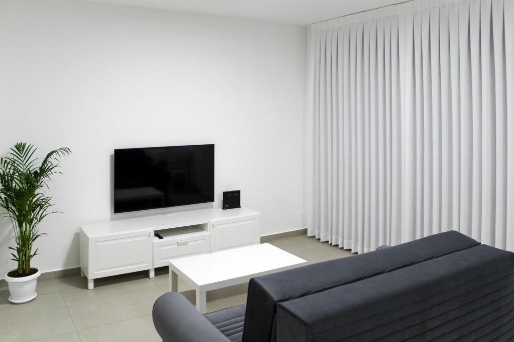 a living room with a couch and a tv at Luxury Family Apartment #30 By Hashdera Eilat in Eilat
