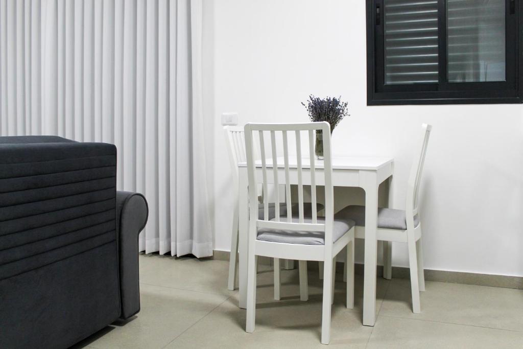 a white table with two chairs and a white table and chairsearcher at Luxury Family Apartment #30 By Hashdera Eilat in Eilat