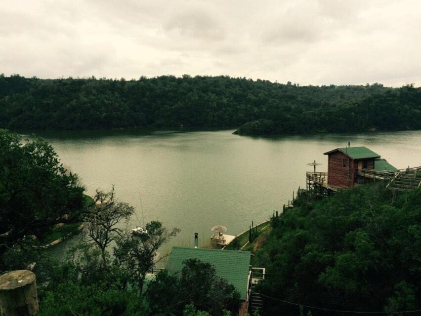 a view of a lake with a building on a hill at Cabañas Quillay Viejo in Lago Rapel