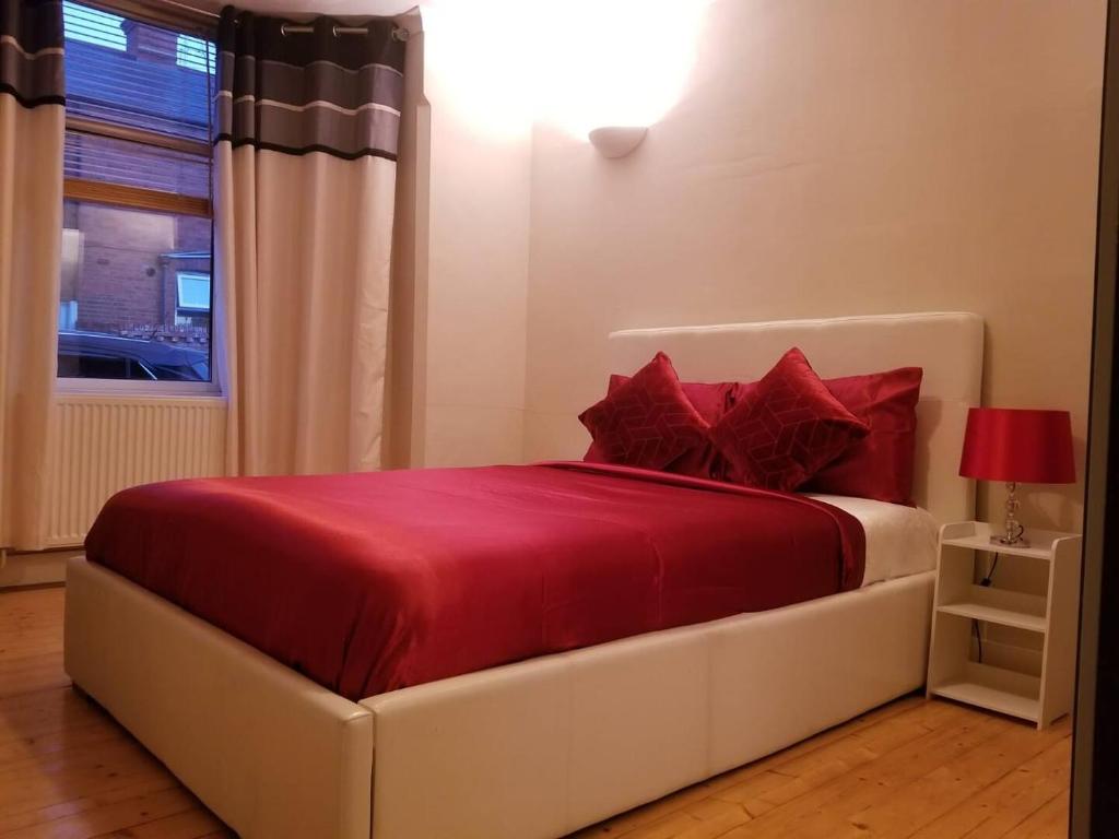 Schlafzimmer mit einem Bett mit roten Kissen und einem Fenster in der Unterkunft Central Reading 4 Bedrooms 2Baths Free Parking in Reading