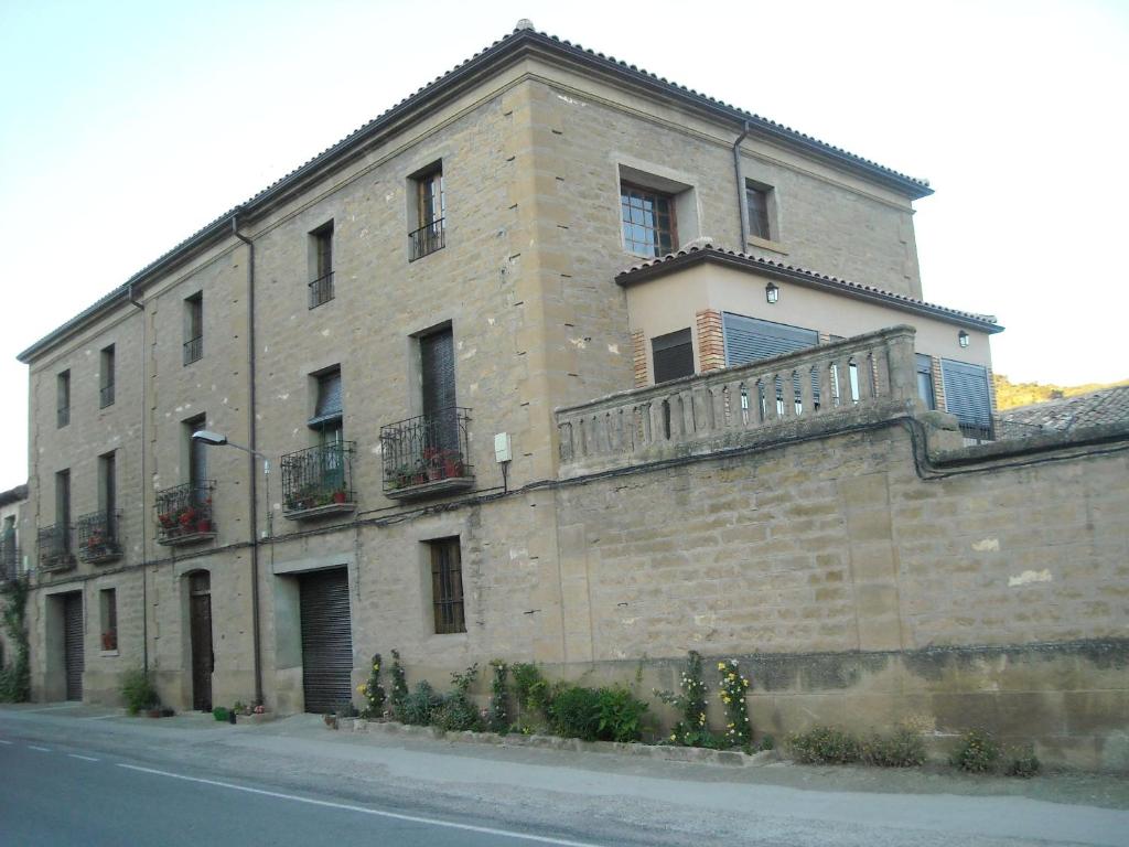 a large brick building with a balcony on a street at Casa Carrera Rural in Biscarrués