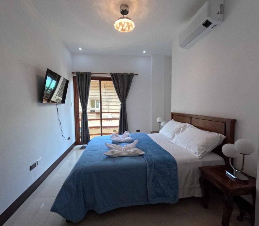 a bedroom with a bed with a blue blanket and a window at Angel Wish Guesthouse in El Nido
