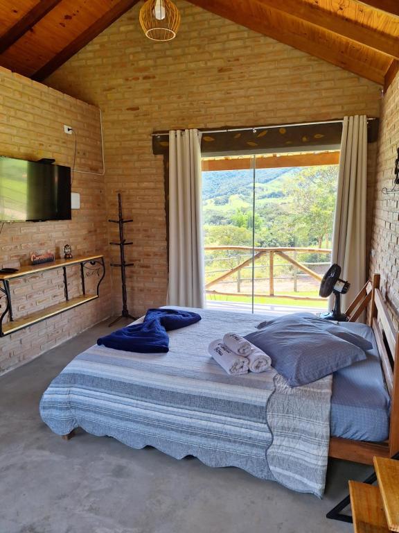 a bedroom with a large bed with a large window at Chalés de Hórus in São Thomé das Letras
