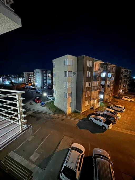 a parking lot with cars parked in front of buildings at Lindo Departamento y muy acogedor in Curicó