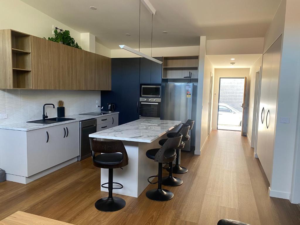 a kitchen with a counter and stools in it at Luxe & Superior 2BR Villas Patio Free Parking & Wifi in Launceston