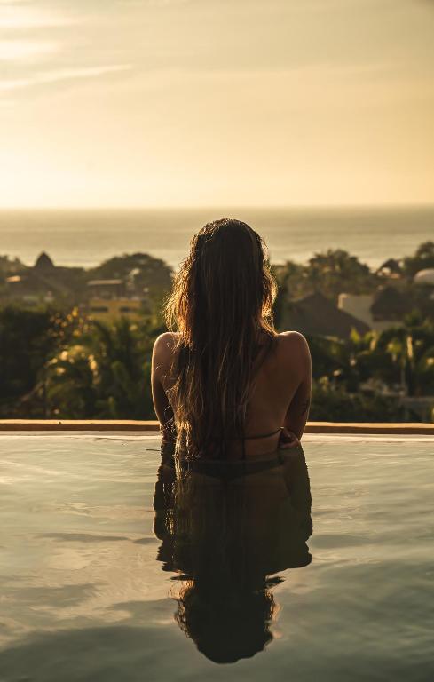 a woman sitting in a bath tub looking at the ocean at Villa Macarena Apartamentos Boutique - Only Adults in Puerto Escondido