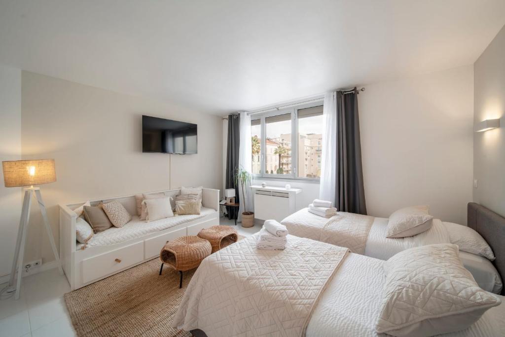 - une chambre blanche avec 2 lits et un canapé dans l'établissement Cosy Studio located 2 minutes from the famous Croisette, à Cannes