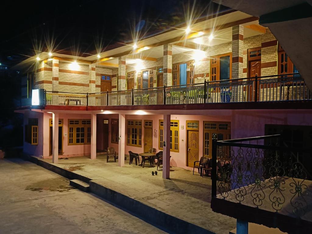 um edifício com uma varanda à noite com uma mesa em Chojh Inn Guest House em Kasol