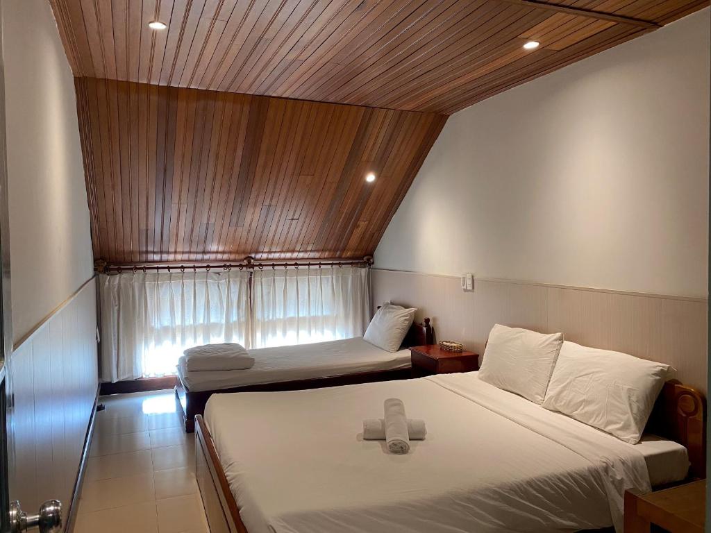 um pequeno quarto com 2 camas e uma janela em Harmony Old Town Hostel and Pool Bar em Hoi An