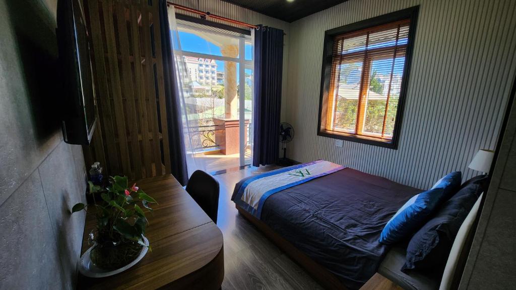 een slaapkamer met een bed, een tafel en een raam bij Twin Villa Village Đà Lạt in Da Lat