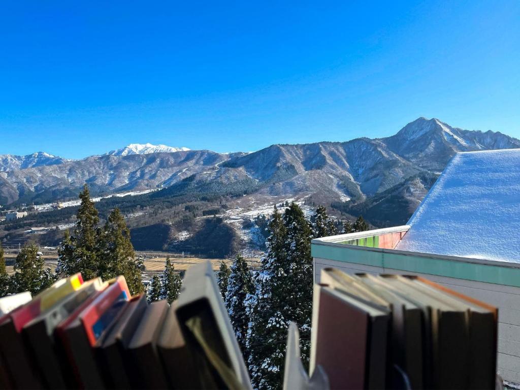 Ein Haufen Bücher auf einem Regal mit Bergen im Hintergrund in der Unterkunft Ishiuchi Ski Center - Vacation STAY 09200v in Seki