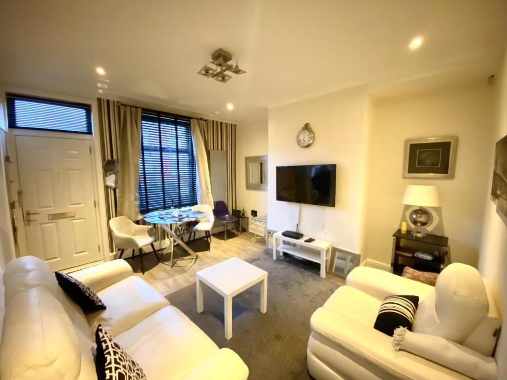 a living room with white furniture and a tv at Leeds City House in Leeds