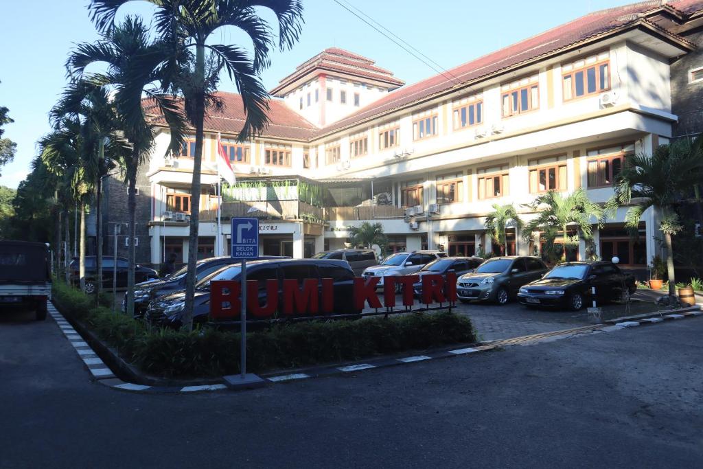 a building with cars parked in a parking lot at Hotel Bumi Kitri in Bandung
