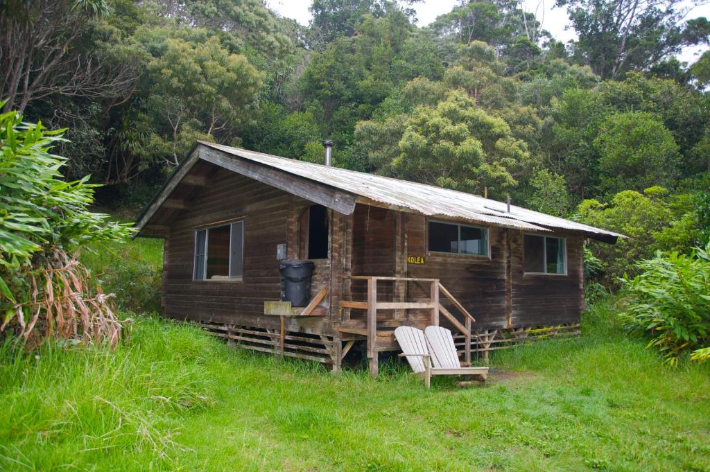 une petite cabane en bois avec deux chaises dans l'herbe dans l'établissement The Cabins at Kokee, à Waimea