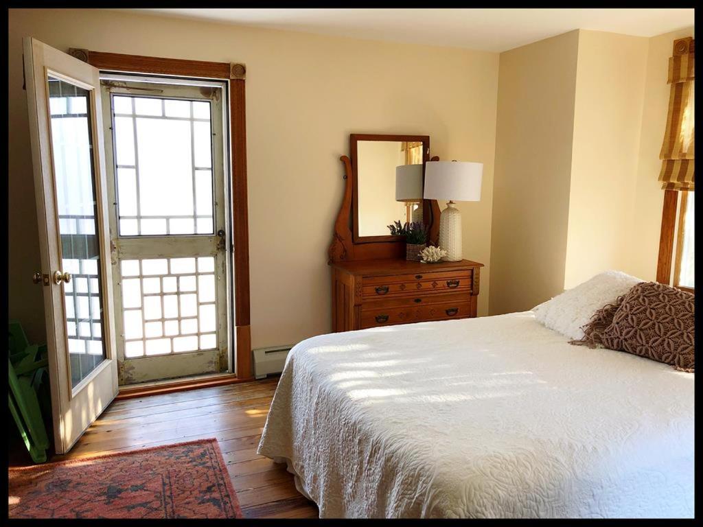 a bedroom with a bed and a mirror and a window at Beautiful Victorian Home On Ocean Side, in Waretown