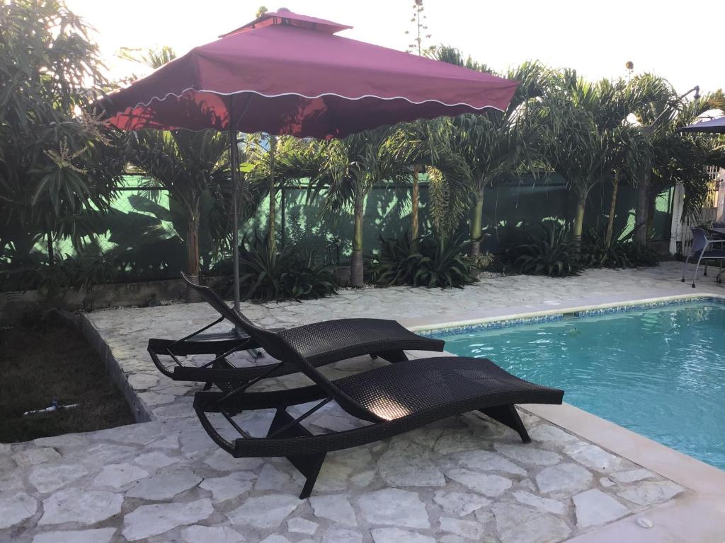 a chair and an umbrella next to a swimming pool at Villa Nilsa ( The Blue House ) in Baní