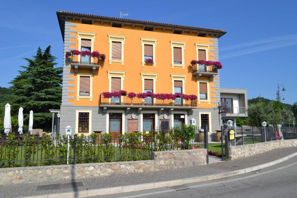 a orange building with flower boxes and a fence at Locanda La Sosta in Cavaion Veronese