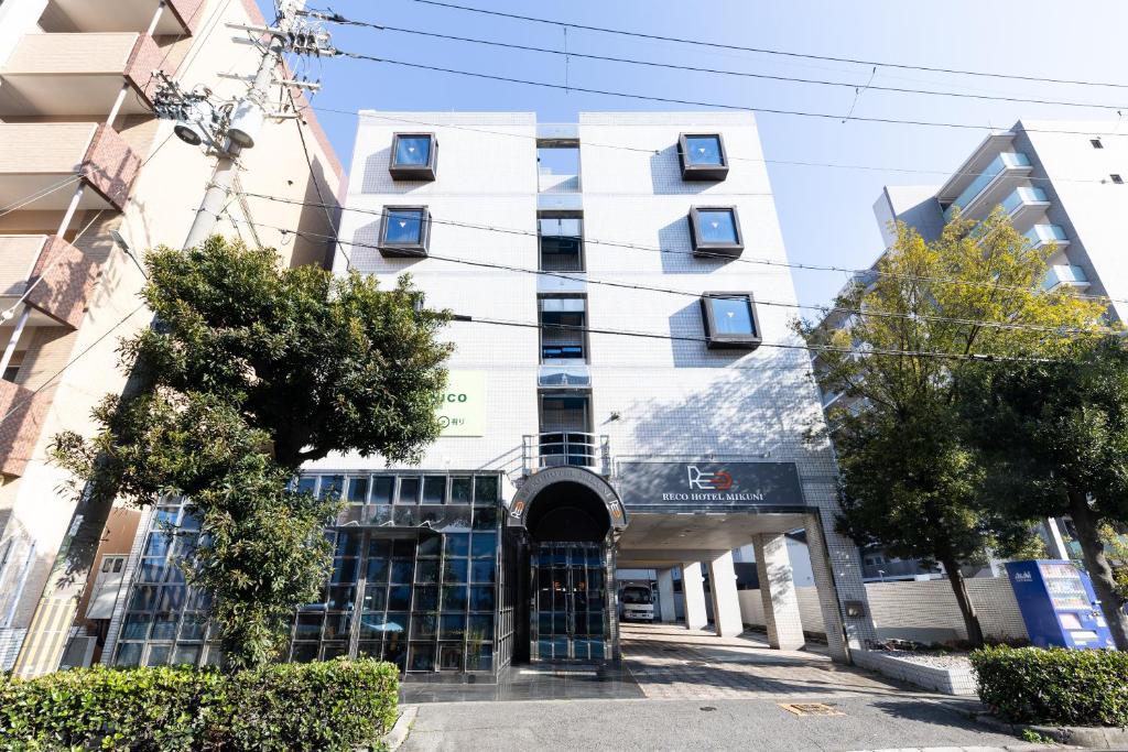 un edificio bianco con ingresso ad esso di Reco Hotel Mikuni a Toyonaka