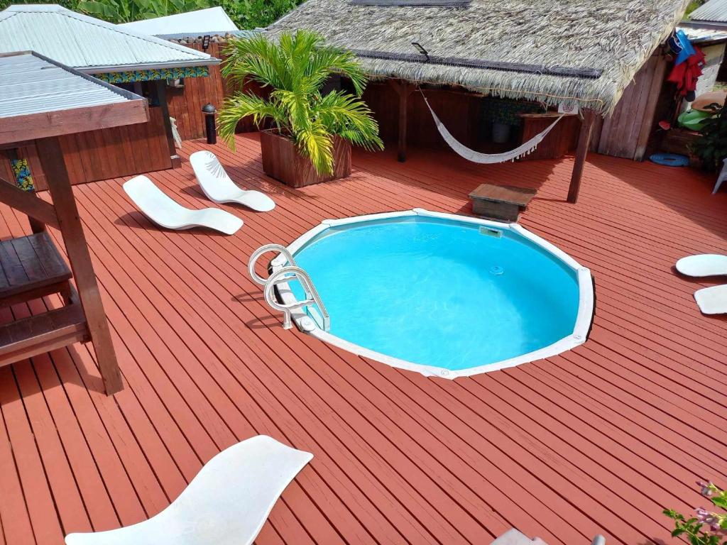 una piscina en una terraza con sillas y una hamaca en Pension LE PASSAGE vu mer, en Vaitoare