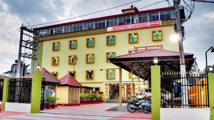 Tezpur的住宿－Hotel Angel Assam，停在前面的黄色建筑,有一辆摩托车