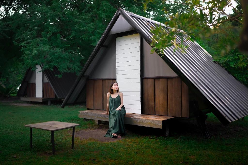 a woman is standing in front of a house at ปิติฟาร์มมิลี่ คาเฟ่&แกลมปิ้ง ผามออีแดง in Ban Phumsaron