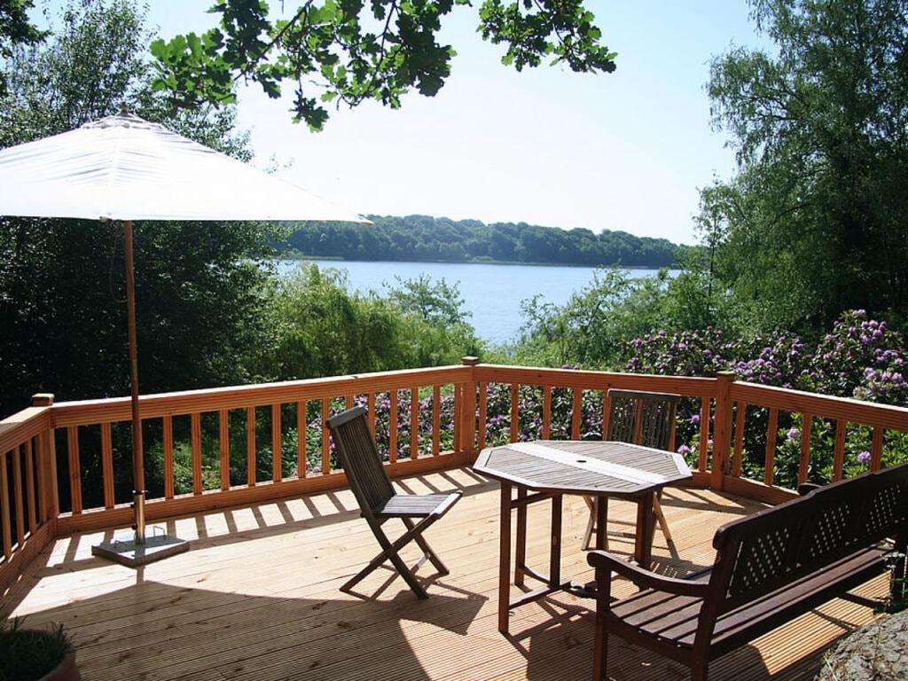une terrasse en bois avec une table, des chaises et un parasol dans l'établissement Hollstein house by the lake, à Stolpe