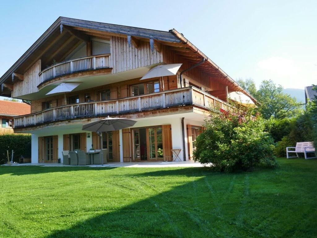 a large house with a balcony and a lawn at Bodenschneid Suites Wallbergblick in Rottach-Egern