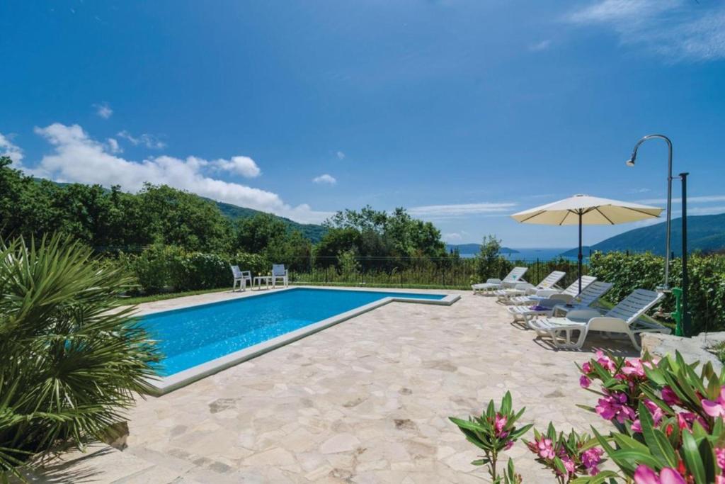 a swimming pool with chairs and an umbrella at Pool Villa Panorama Mojdež - Happy Rentals in Igalo