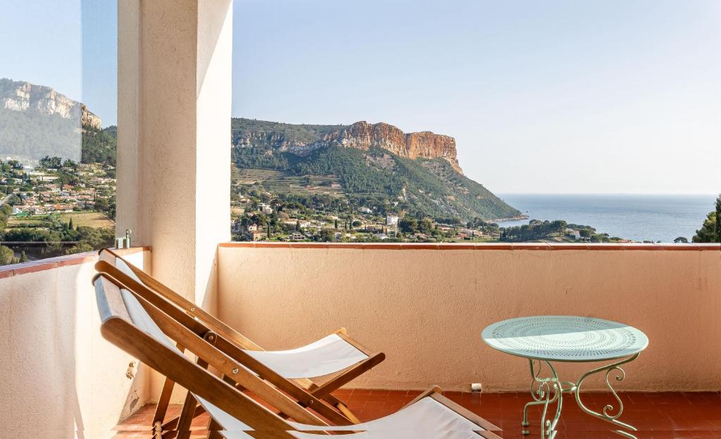 ein Tisch und Stühle auf einem Balkon mit Blick auf das Meer in der Unterkunft Les Aiguadines par Dodo à Cassis in Cassis