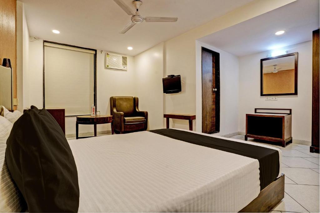 Schlafzimmer mit einem Bett, einem TV und einem Stuhl in der Unterkunft Super OYO Flagship Hotel Golden Nest in Saravli