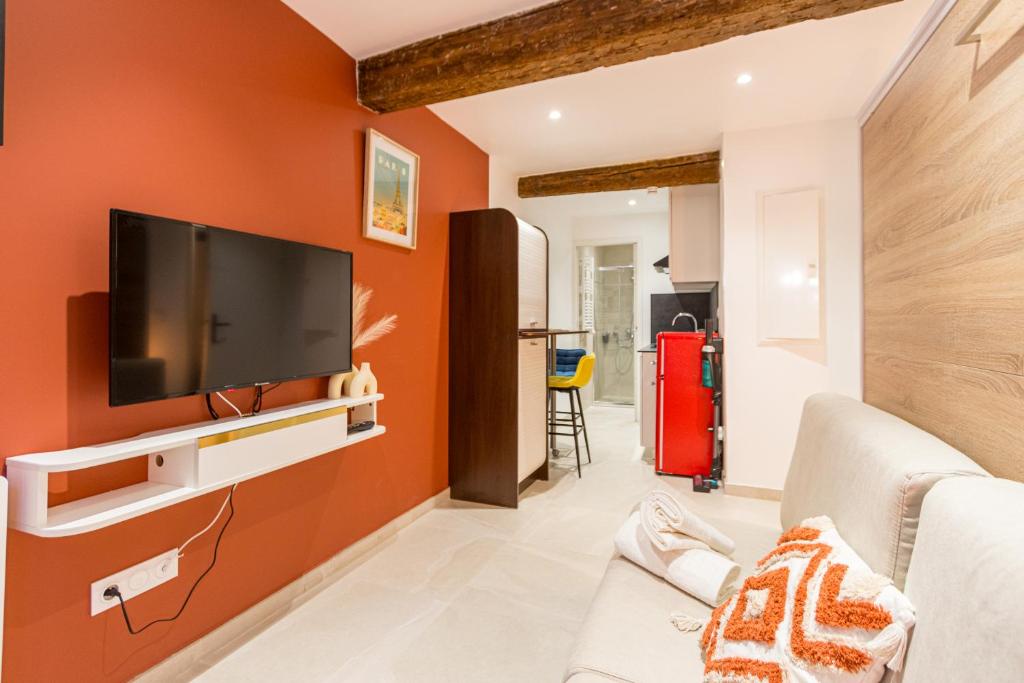 een woonkamer met oranje muren en een flatscreen-tv bij Charmant Studio Neuf N•2 - Centre ville in Montpellier