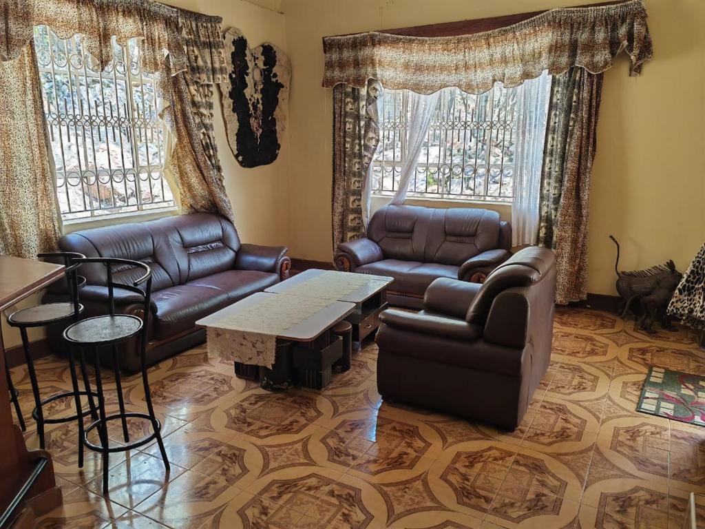 D-TURA Guest House في Sekenani: غرفة معيشة مع كنب وطاولة وكراسي