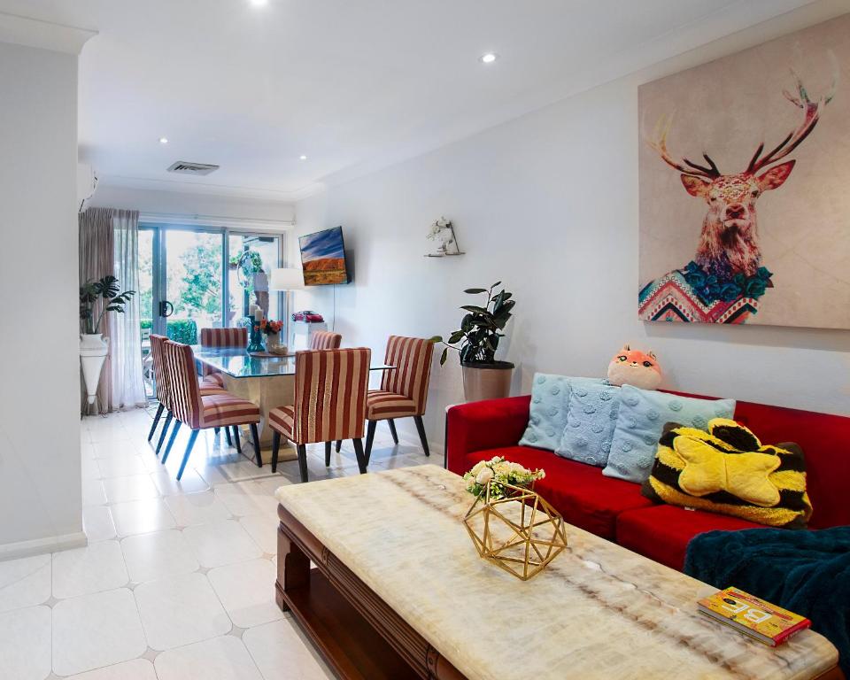 uma sala de estar com um sofá vermelho e uma mesa em Sydney Charm & Blissful Casa - 2 min walk to bus 10 min drive to Sydney Olympic Park em Sydney