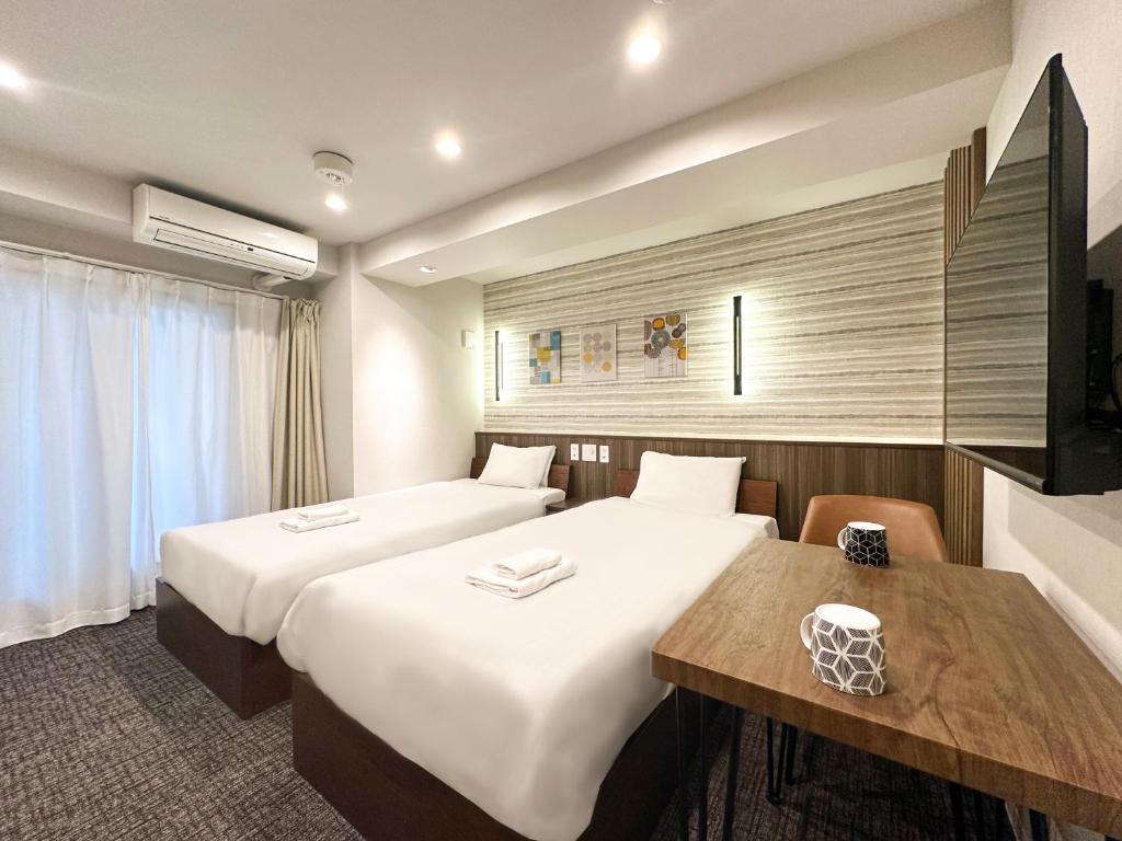 a hotel room with two beds and a table at Osaka Ebisu Hotel in Osaka