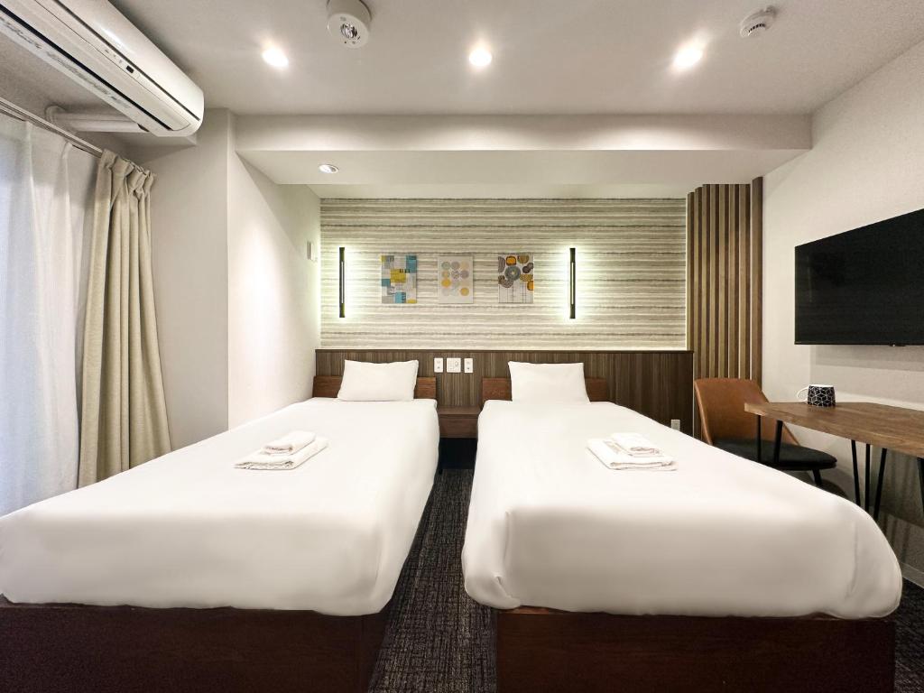 a hotel room with two beds and a desk at Osaka Ebisu Hotel in Osaka