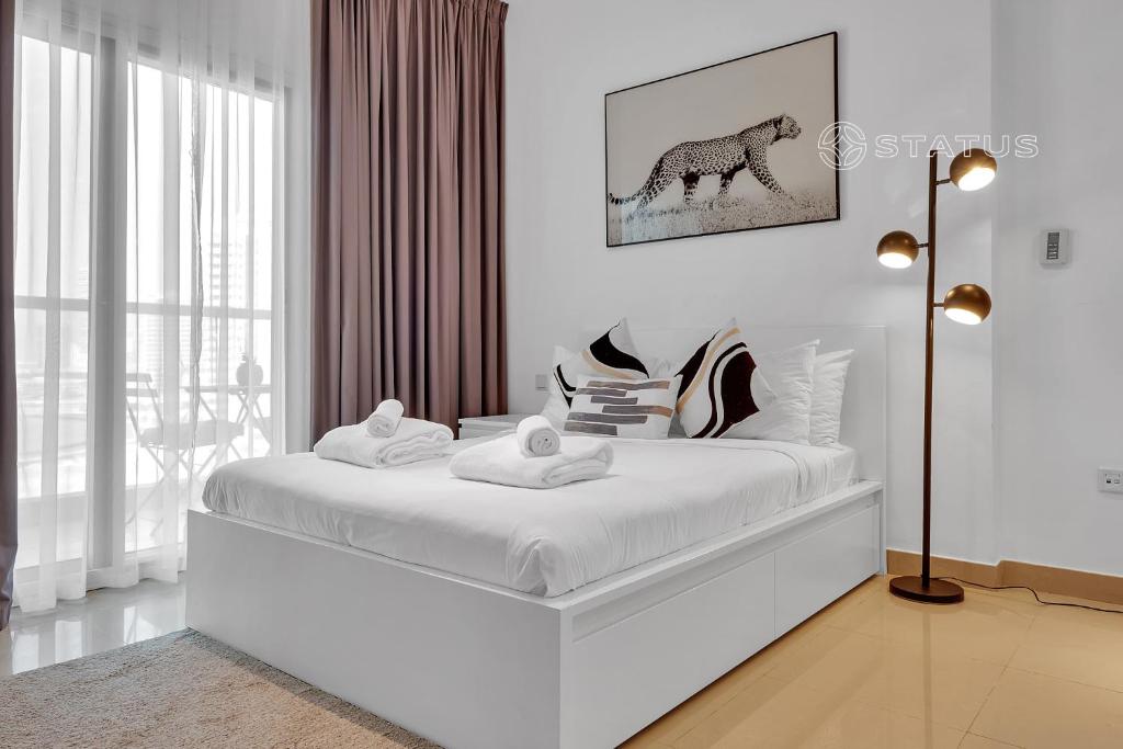 a white bedroom with a white bed with a picture of a horse at Sleek Studio - Red Residence-L8 - Near ISD Stadium in Dubai