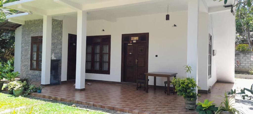 - une terrasse couverte à l'avant d'une maison avec une porte en bois dans l'établissement Sundill Green Homestay, à Tangalle