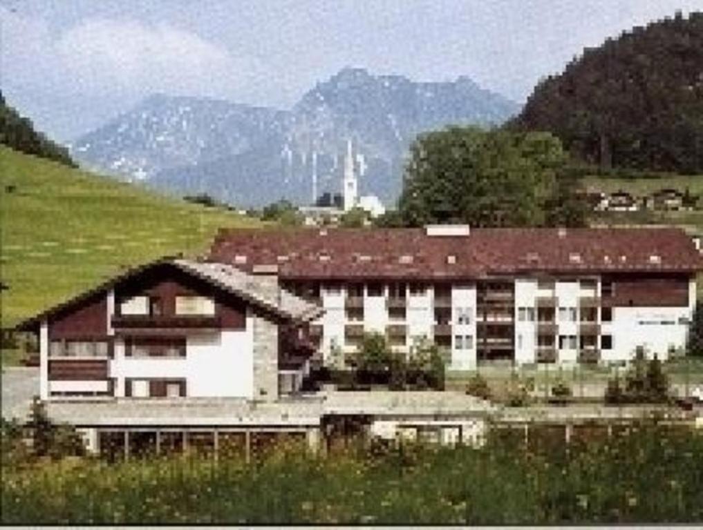 un grand bâtiment dans un champ avec des montagnes en arrière-plan dans l'établissement Studio Haus Falkenberg Nr 201 mit Balkon in Oberstdorf-Tiefenbach, à Oberstdorf