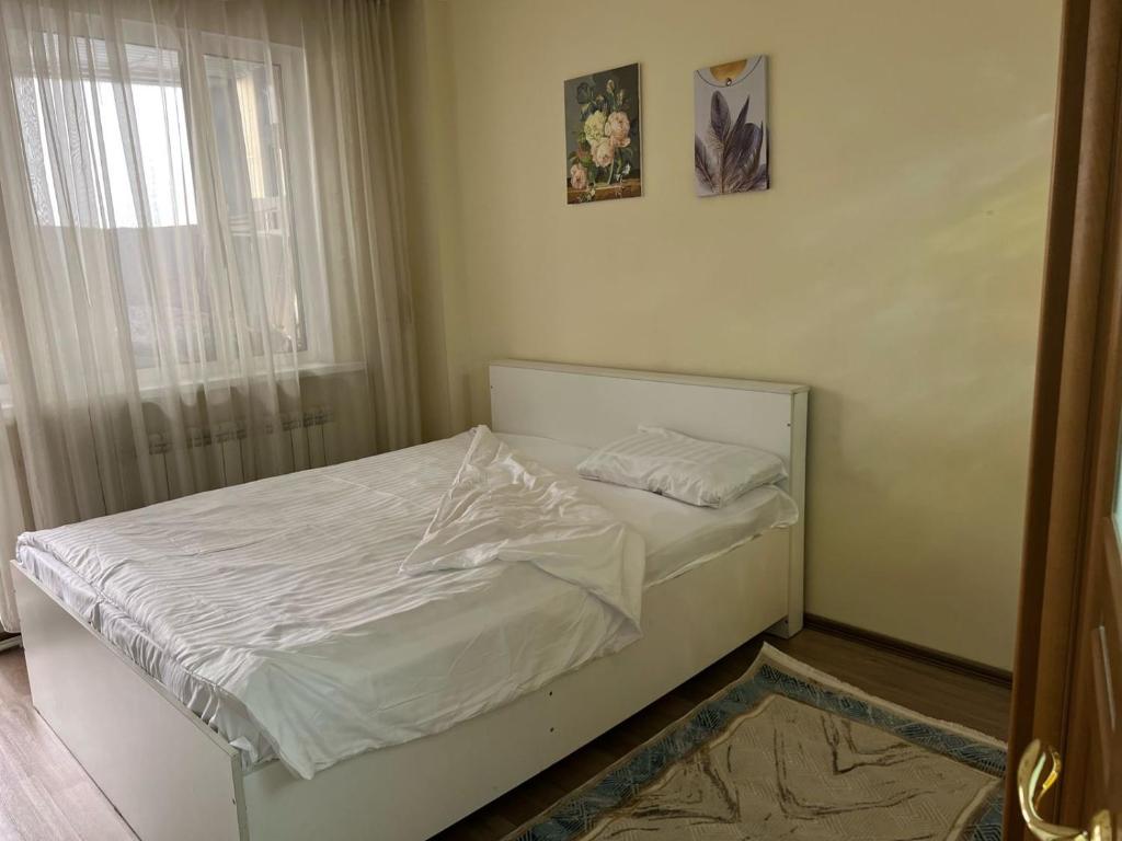 un piccolo letto in una camera con finestra di Квартира a Astana