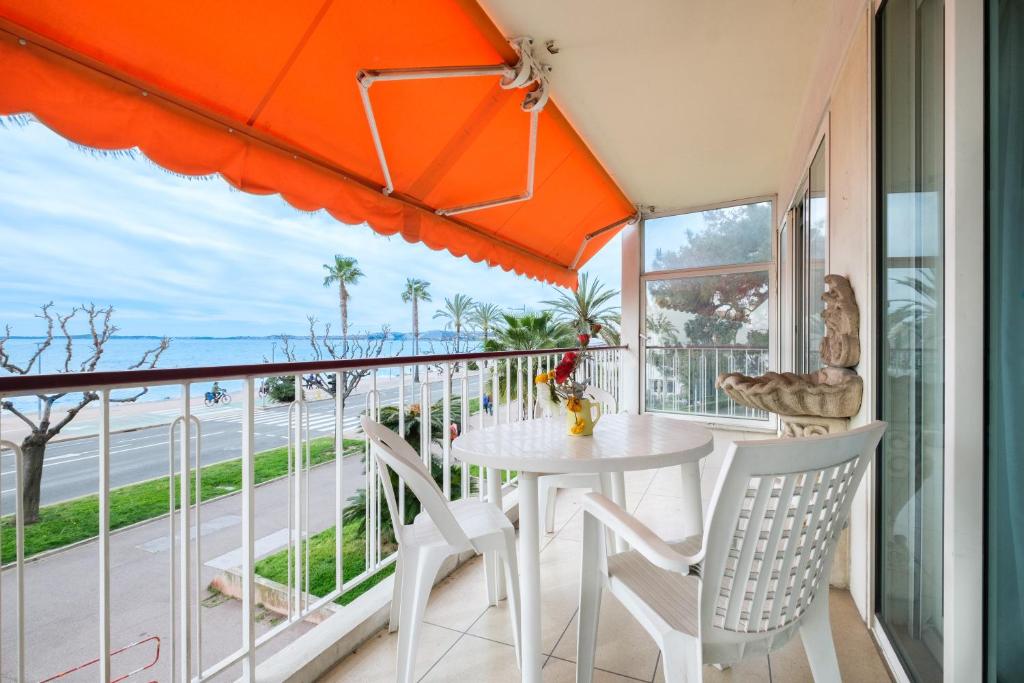 a balcony with an orange umbrella and a table and chairs at Angelina - La002 in Cagnes-sur-Mer