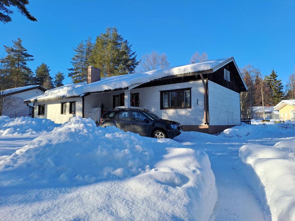 a car parked in front of a house covered in snow at Traditional House Rovaniemi in Rovaniemi