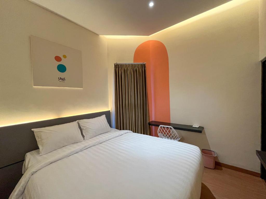 a bedroom with a white bed and an orange wall at SANS Hotel Premiere Majapahit Semarang in Semarang