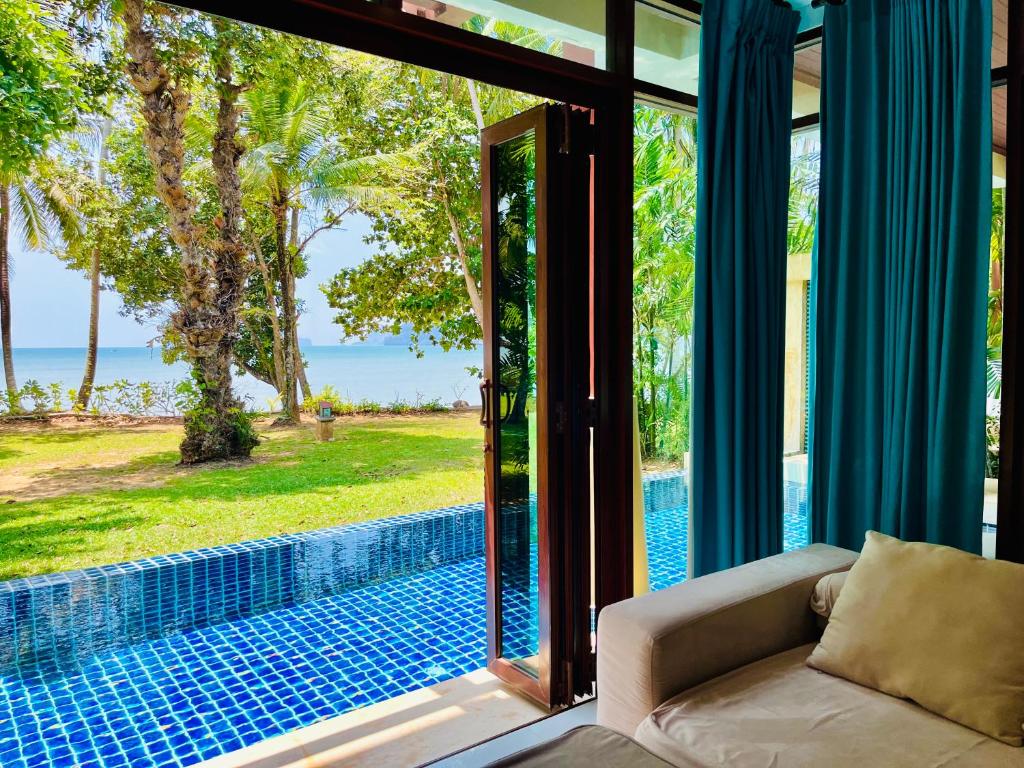 a living room with a couch and a view of a swimming pool at Amatapura Beachfront Villa 14, SHA Certified in Ao Nam Mao