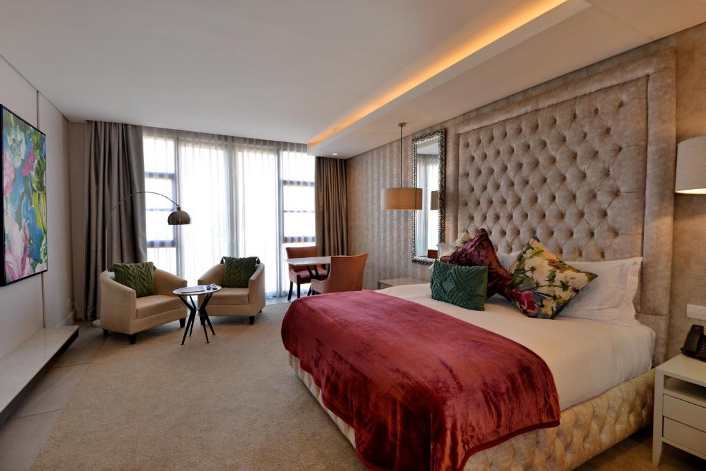 um quarto de hotel com uma cama grande e uma sala de estar em Houghton Suites em Joanesburgo