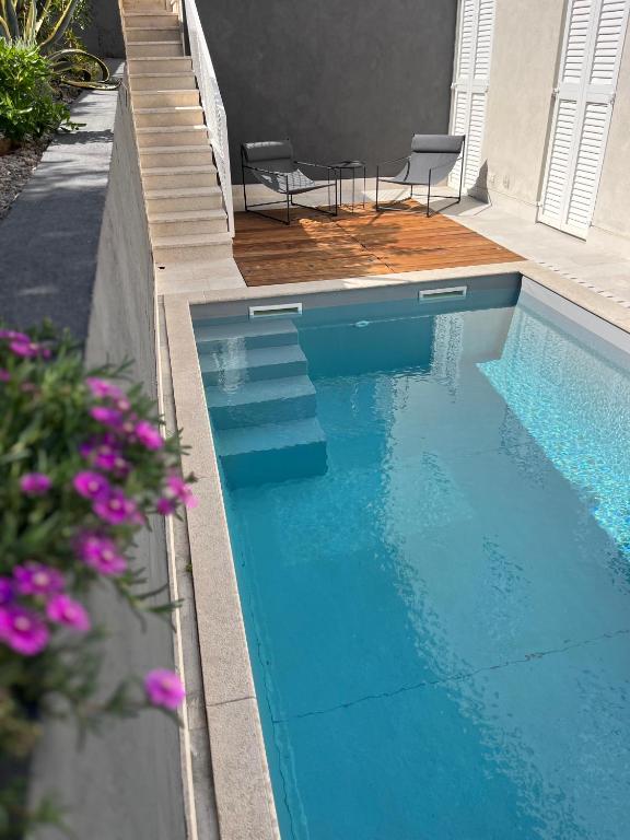 a swimming pool with two chairs and some flowers at Apartment Arte Vrbnik in Vrbnik