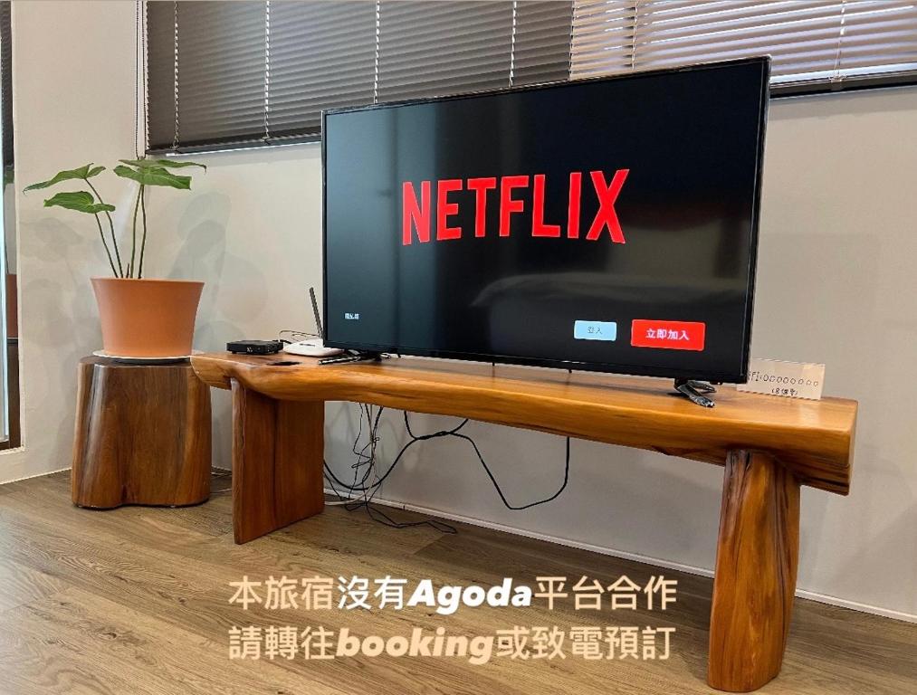 uma televisão numa mesa de madeira com o sinal de netflix em Rightday Inn em Dongshan