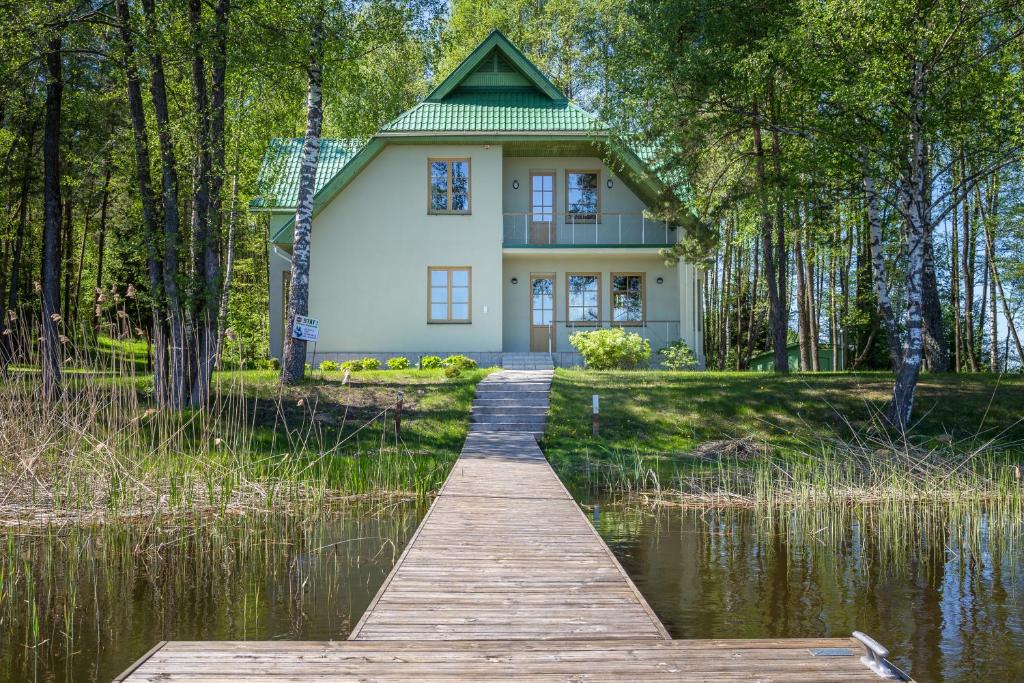 a house on a lake with a wooden walkway at Pussala in Daugavpils