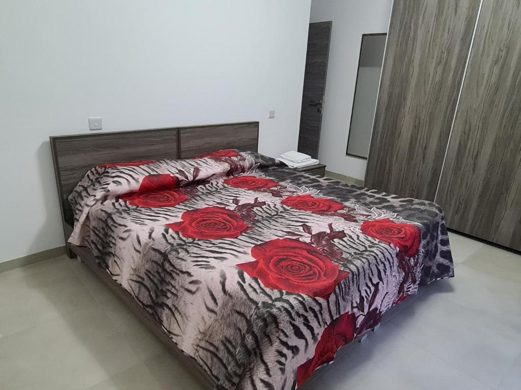 a bedroom with a bed with red roses on it at Cescaren Gozo Ghajnsielem in Għajnsielem